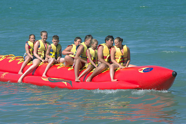 le persone cavalcano su zattera gonfiabile a forma di banana - women courage water floating on water foto e immagini stock