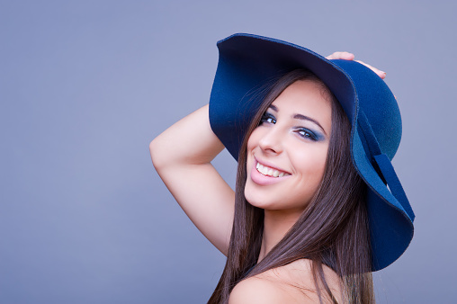 Beautiful girl with blue hat, smiling. Studio shot.