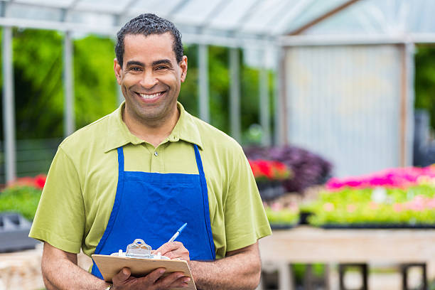 mitarbeiter des gartencenters prüft inventar im gewächshaus - clipboard men sales occupation casual stock-fotos und bilder