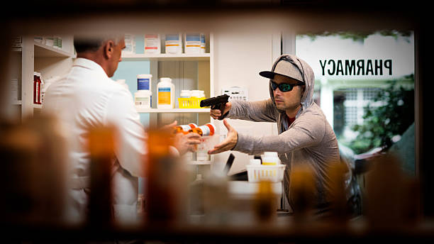 Armed Robbery An armed robber pointing a pistol at an pharmacist and demands drugs and prescriptions. stealing crime stock pictures, royalty-free photos & images