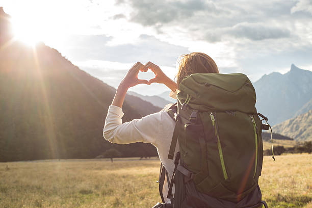 istock Woman makes heart shape finger frame over mountain landscape 546011520