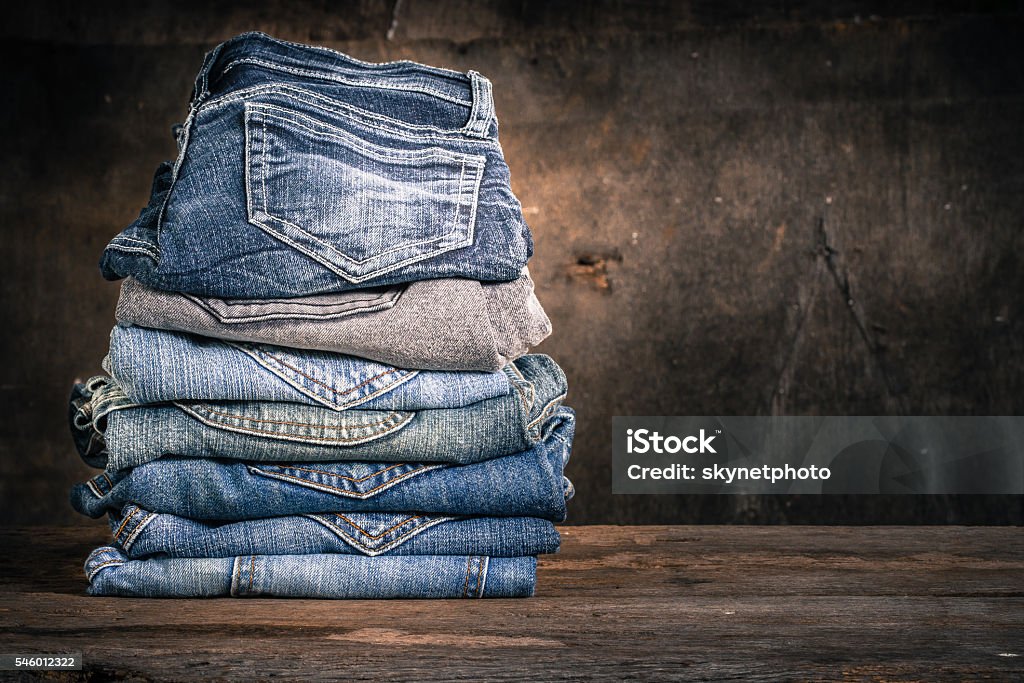 Jeans stack vintage Close up of many jeans trouser stack on wooden vintage background Jeans Stock Photo