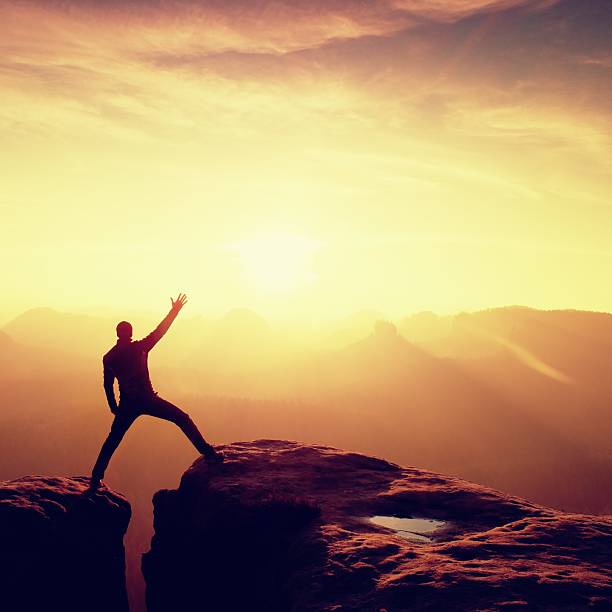 istock Jumping hiker in black triumph between rocky peaks. 546018250