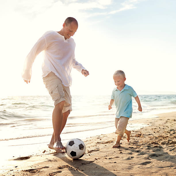 istock Father Son Playing Soccer Beach Summer Concept 546020916