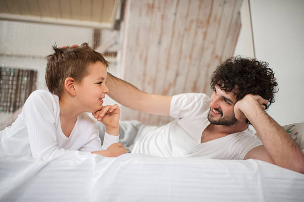 istock Small boy and his father relaxing on bed and talking. 546022526