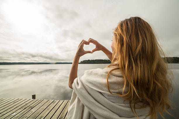 istock Female makes heart shape finger frame to mountain lake landscape 546024732
