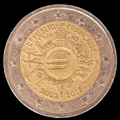 A commemorative circulated two euro coin issued by France in 2012 and celebrating the ten years of the Euro. Image isolated on black background.