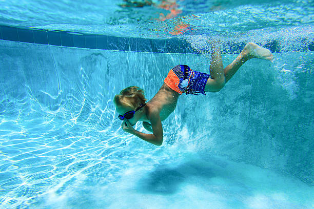 istock little boy learns swimming underwater 546164328