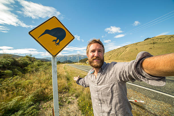 istock Young man takes self portrait with Kiwi warning sign, NZ 546164976