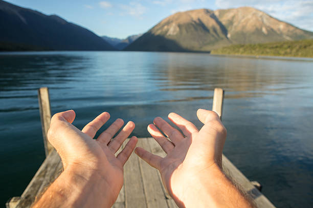 Close up on man's hands cupped in the nature. Personal perspective of man embracing the nature. Shot on the lake Rotoiti on the New Zealand's South Island.
