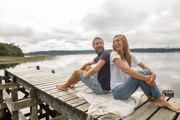 istock Cheerful young couple relaxing on lake pier 546173606