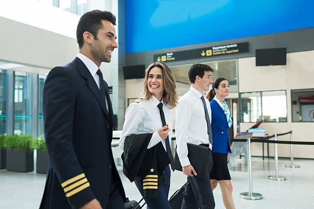 equipaggio dell'aereo che cammina nel terminal dell'aeroporto vicino all'ufficio della compagnia aerea. - piloting foto e immagini stock