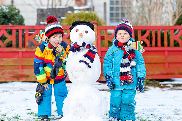 istock Two little siblings boys making a snowman in winter 546176720