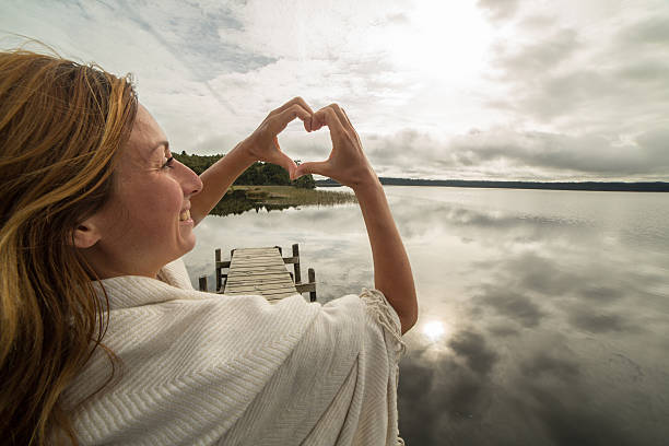 istock Woman frames mountain lake landscape into heart shape 546177590