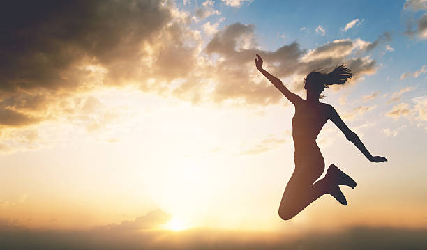istock Young woman jumping outdoors at sunset 546180920
