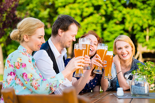 Friends toasting with beer in garden restaurant
