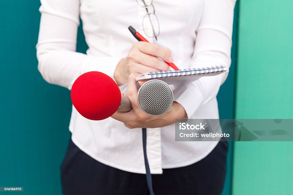 Journalist at media event. News conference. Female journalist or reporter at press conference, taking notes, holding microphones Journalist Stock Photo