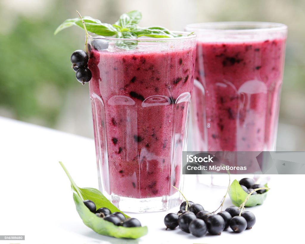 Best Berry Smoothie Drink in Red Best Berry Smoothie Drink in Red. Beautiful smoothie, vegan recipe, two glasses, berries, basil green leaves. Summer time  Black Currant Stock Photo