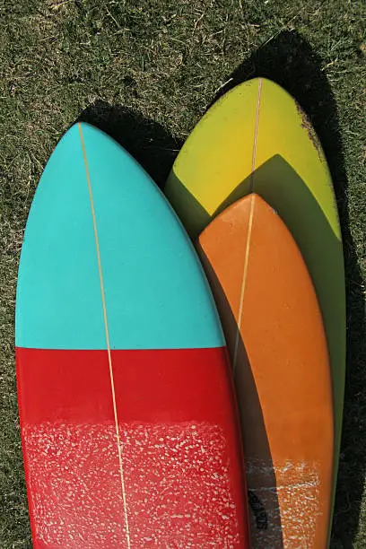 Tree surfboard on each other in different shapes and colors on grass