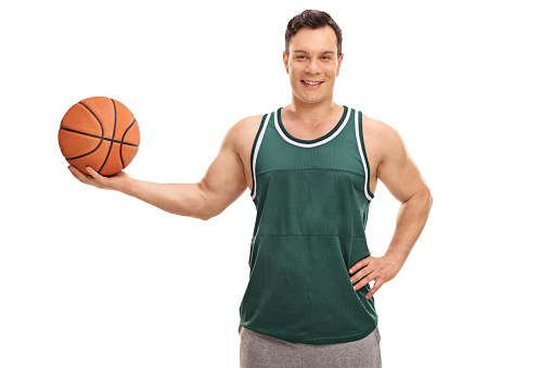 Joyful young man in a green jersey holding a basketball isolated on white background