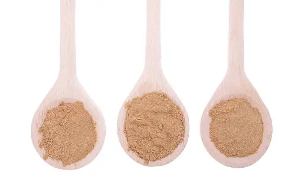 Mesquite powder in wooden spoon isolated in white background
