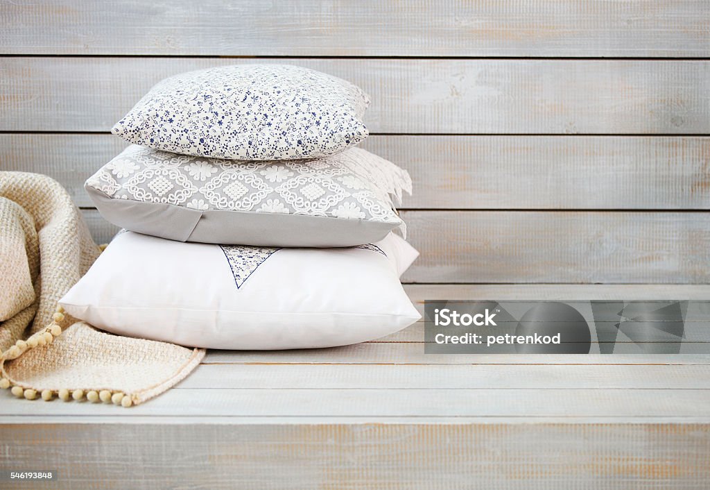 Cozy pillows and plaid on the light wooden background Cozy pillows and plaid on the light wooden background. Close up Pillow Stock Photo