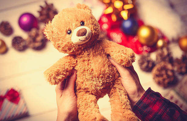 child hands holding a teddy bear stock photo