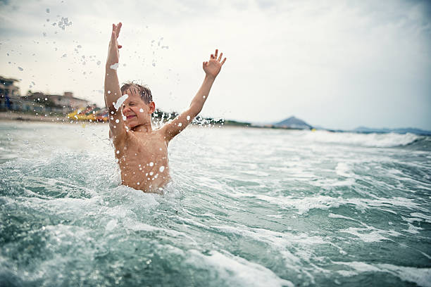 istock Little boy splashing in cold sea waves 546196652