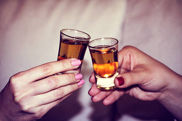 two woman hands toasting whiskey, brandy with isolated backgroun - shot glass imagens e fotografias de stock