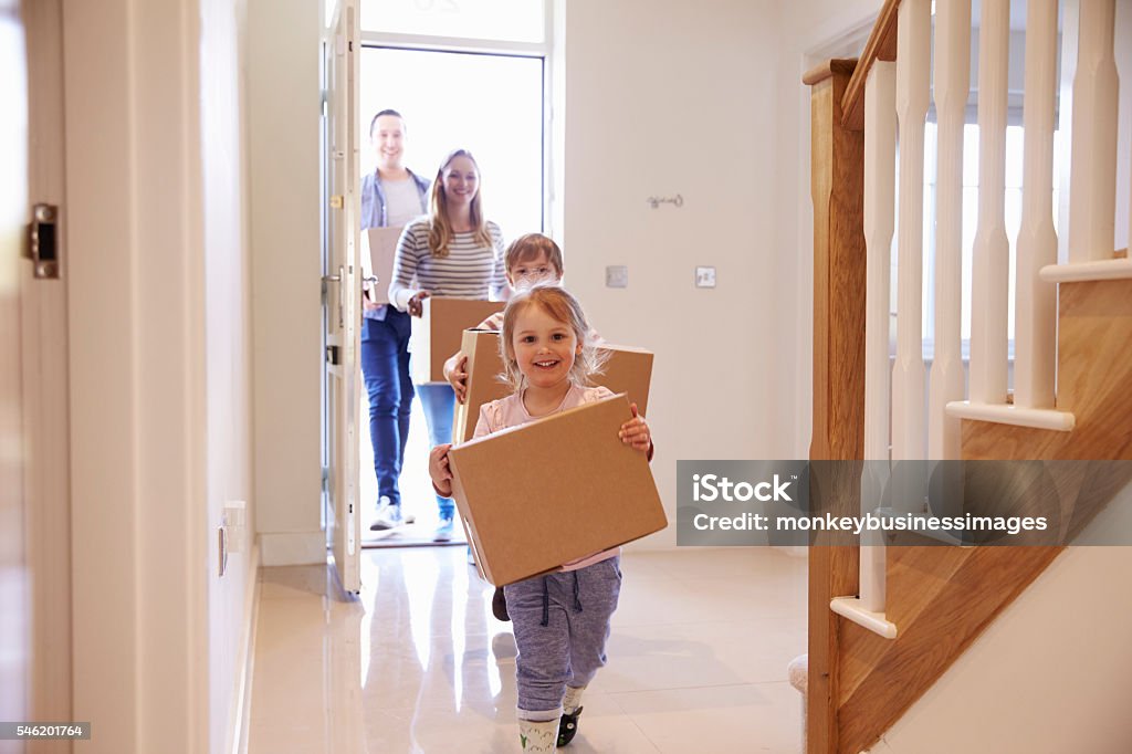 Family Carrying Boxes Into New Home On Moving Day Moving House Stock Photo
