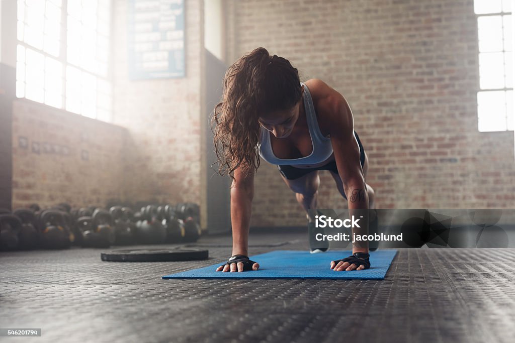 Young muscular woman doing core exercise Young muscular woman doing core exercise on fitness mat in the gym. Fit female doing press-ups during the training in the health club. Push-ups Stock Photo