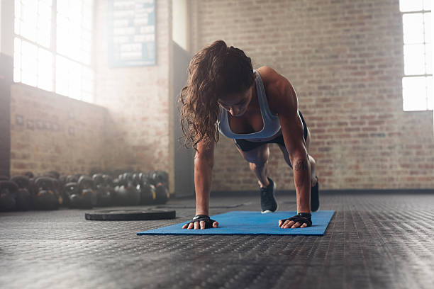 Young muscular woman doing core exercise Young muscular woman doing core exercise on fitness mat in the gym. Fit female doing press-ups during the training in the health club. push ups stock pictures, royalty-free photos & images