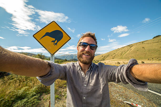 istock Young man takes self portrait with Kiwi warning sign, NZ 546203604