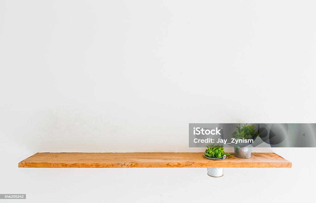 Wooden shelf on white wall with green plant. Abstract Stock Photo