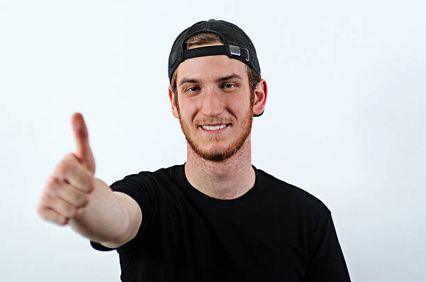 sorrindo jovem adulto masculino mostra seus polegares para cima - baseball cap men ok thumbs up - fotografias e filmes do acervo