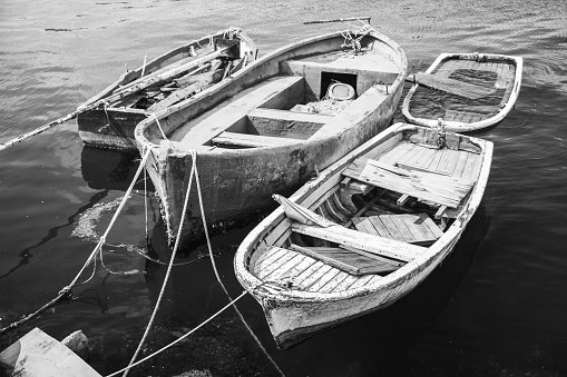 Old wooden fishing boats moored in small port of Avcilar, district of Istanbul, Turkey. Black and white retro stylized photo