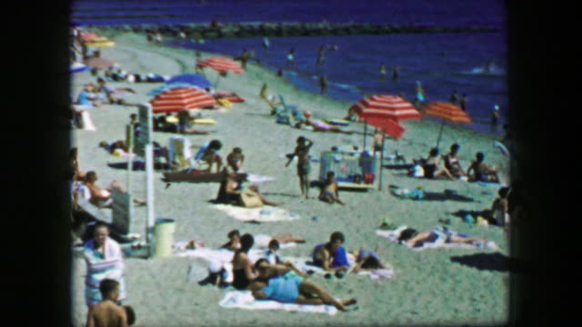 1959: Cape Cod summer beach umbrella sand colorful vacation.