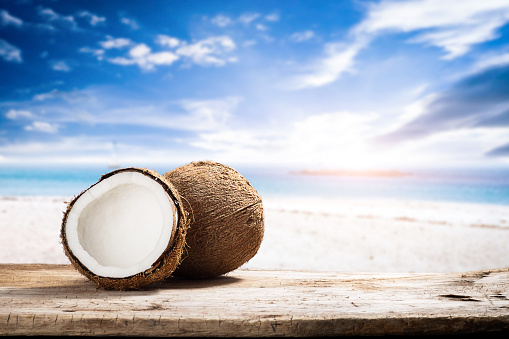 Fruits of coconuts on desk space over sea scape background.
