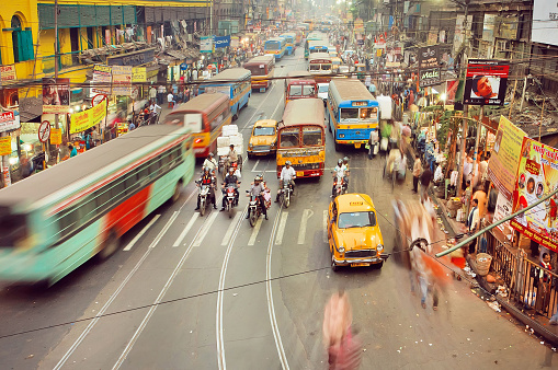 Kolkata, India - January 17, 2013: Motion blurs from public buses, cars and rushing people on indian road with many stores on January 17, 2013. Kolkata has a density of 814.80 vehicles per km road length