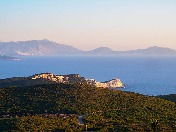 Road to Cape Lefkas on Lefkada, Greece Road between pines to remote Cape Lefkas lighthouse on Lefkada, Greece in the evening looking towards Ikaria ikaria island stock pictures, royalty-free photos & images
