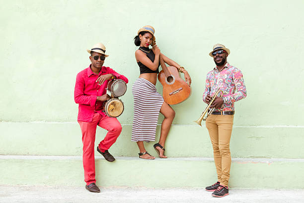 Cuban Musical Band Outdoors Cuban musical band, the trio consisting of a fairly well-known musicians standing outdoors, on the steps, against the bright green wall. Beautiful young woman standing in the middle, holding a guitar. The man on the left holding the small drums bongos, and a musician on the left holding a trumpet. Havana, Cuba, 50 megapixel image. salsa music photos stock pictures, royalty-free photos & images