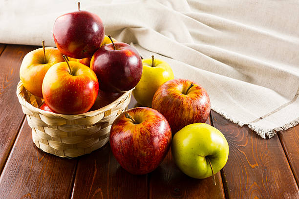 istock Apples in the small wicker basket on dark wooden background 546424826