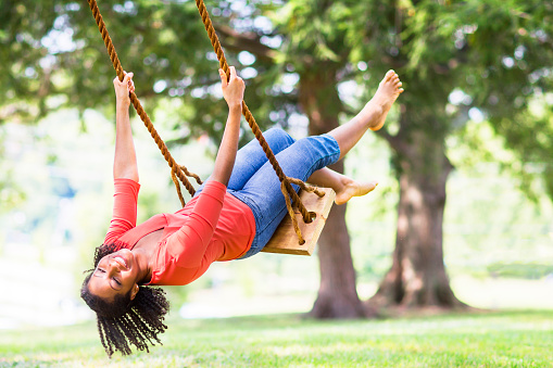 Young woman on a rope swing outdoors in the park.