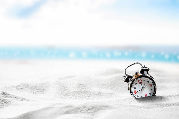 Alarm clock sink to sand on beach side blue sky. stock photo