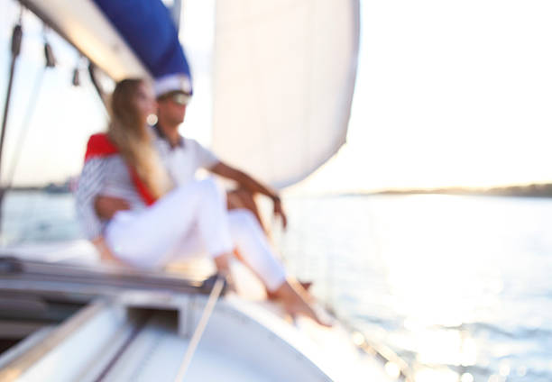 Blurred background with couple stting on sailboat deck looking at sealine