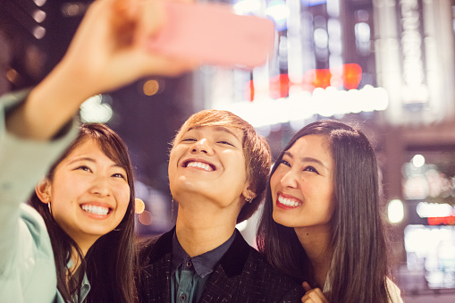 Happy friends in Osaka city taking selfie together