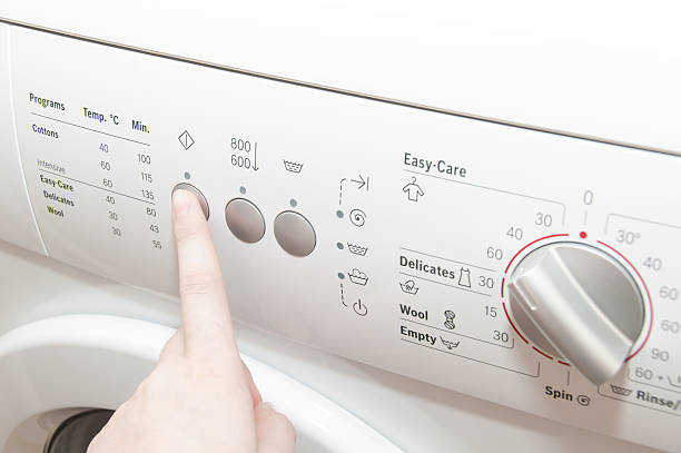 istock Close up of woman choosing cycle program on washing machine 546430482