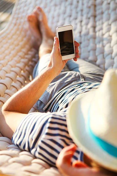 Man in a hammock with mobile phone on summer day