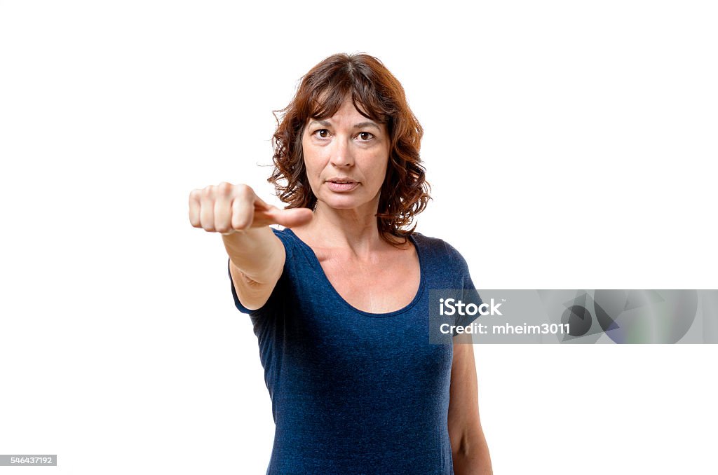 Middle-aged woman abstaining from voting Attractive middle-aged woman abstaining from voting indicating her indifference or neutrality with her thumb to the side, isolated on white Adult Stock Photo