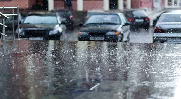 istock Heavy rain drops on asphalt with parked cars  background 546438458